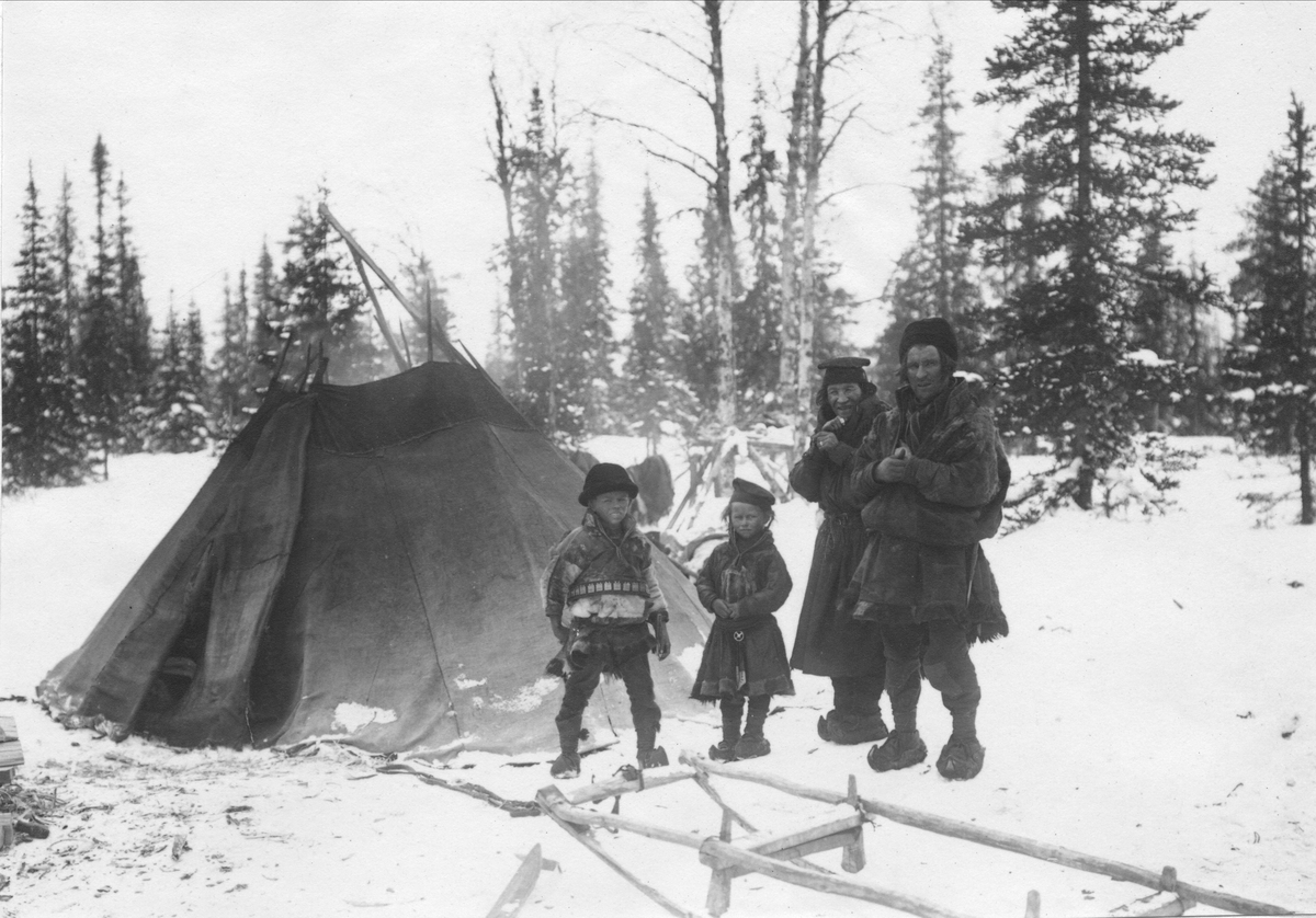 Kvinna, man och två barn i snön utanför kåta i Gällivare lappmark.