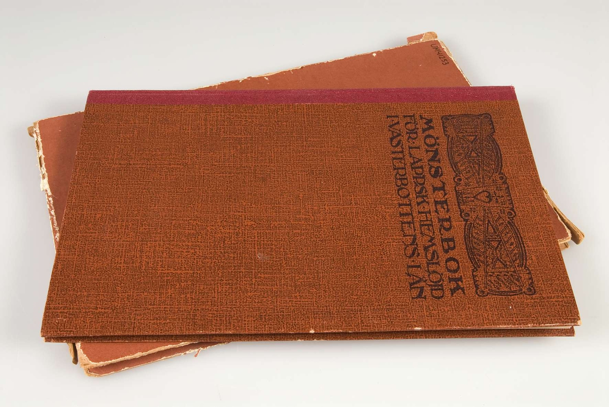 Tryckt bok med pärmar av papp. Pärmarna är klädda med brunmönstrat papper och bokryggen är klädd med vinröd klot. På framsidan är en bild och titeln "MÖNSTERBOK FÖR LAPPSK HEMSLÖJD I VÄSTERBOTTENS LÄN" tryckt. På sidan två står "HÄLSINGBORG 1920 SCHMIDTS BOKTRYCKERI A.-B."
Till boken finns ett fodral av brun papp.