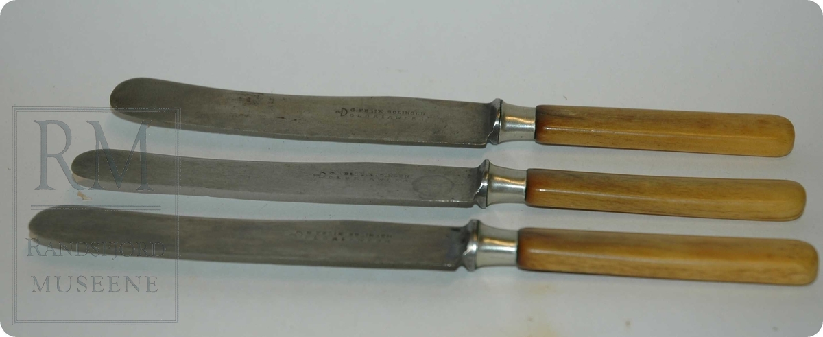 3 stk bordkniver. Avlange, flate stålblad som er festet inn i skaft av gulaktig bein.