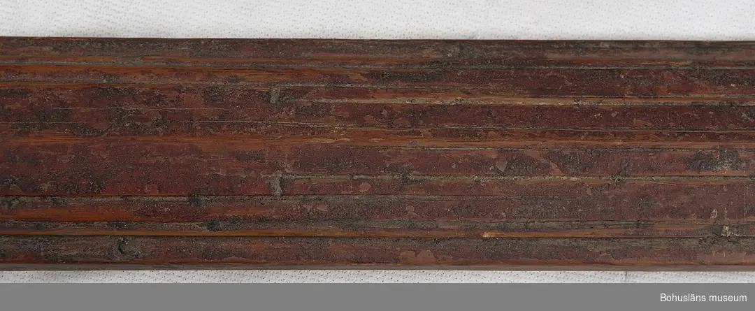 Skidorna har skuret mönster, målade i brunröd färg. Fotgreppet med näver och tvinnade vidjor; bindslen i läder med sölja i metall, skador, delar saknas.
Staven av trä, omålad; trygan/trugan av metall (järn), päls och horn.

Ur handskrivna katalogen 1957-1958:
Skidor, 2st. , + 1 stav
L. 322,5 resp. 225. Träskidor, som tillhört jägaren och förf. L. Lloyd. 1850 - talet.
Stavens L:118 Värmland. Hela staven rostad vid kringlan.

Lappkatalog: 40

Bilagepärmen:
Artikel "Björnjägaren L. Lloyd av William Andrew Macfie, 1913.
Artikel i På skidor, Skidfrämjandets Årsskrift 1942. Jirlow, Ragnar. Ur skidlöpningens hävder i Särna.