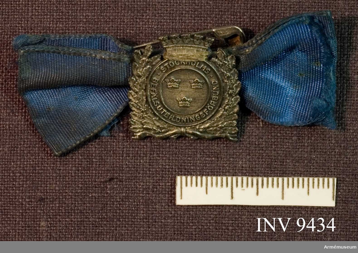 Samhörande nr är 9421 - 9438. 
Medaljen utförd i silver. Stämpel Z 8 synlig på baksidan, d v s 1950. Framsidan har en rund mittskiva i vilken tre kronor (två över en) är inskriven i cirkelrunt band med text "Stockholms befälsutbildningsförbund". Märket är omgivet av ekkvistar och en krona. Märket är fäst i ett blått siden(rips)band.