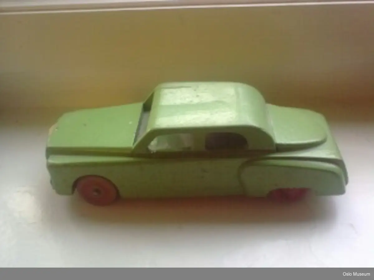 A= grønn lekebil i tre utformet som personbil i typisk 1950-tallsstil
B= rød lekebil i tre utformet som personbil i typisk 1950-tallsstil. Far til giver har risset inn nummerplate og skåret ut bakvindu
C= rød lekebil i plast utformet som personbil i typisk 1950-tallsstil.
D= gul lekebil i metall utformet som sportsbil i typisk 1950-tallsstil.