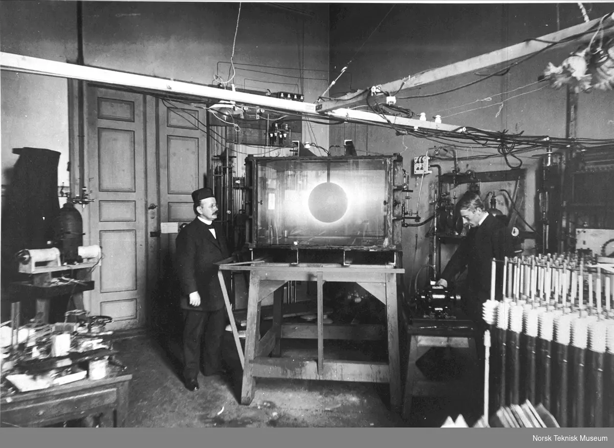 Den norske fysiker Kristian Birkeland (1867-1917) til venstre, og den norske fysiker og administrator Olaf Devik (1886-1987) til høyre, fotografert i laboratoriet under et terrella-forsøk med Birkelands "verdensrom"