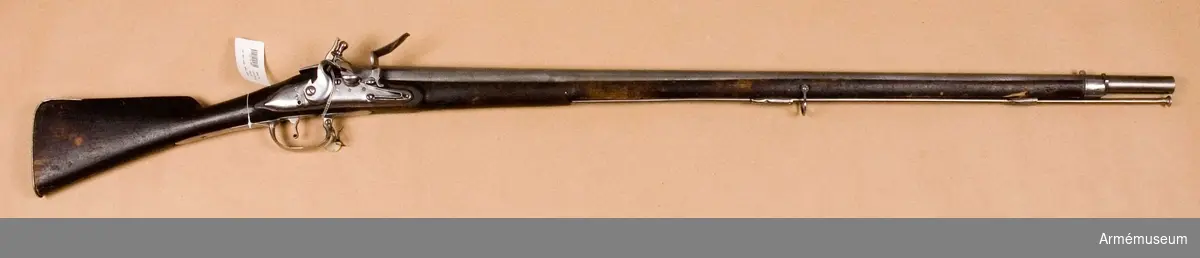 Grupp E II.
Gevär med flintlås.
Kal. 20,3 mm. Sannolikt reparationsmodell från 1700-talets slut. Sammansatt av delar till äldre gevär. Laddstock av järn. Varhaken saknas. Pipan tillverkad i Norrtälje. Märkt "2" över "86", en punkt och "6."