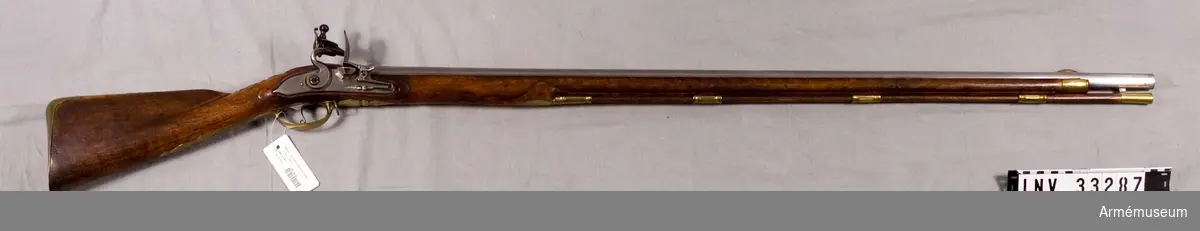 Grupp E II.
Gevär med flintlås, 1730-talet.
Varbygelns längd med främre-bakre arm: 345 mm. Låsets längd: 172 mm, märkt F: Triebel A: Schmalkalten. Sidbleckets längd: 162 mm. Beslag i mässing. Stock i valnöt.