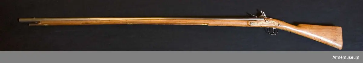 Grupp E XIV.
Loppets relativa längd är 71 kal. Afrikanskt gevär med flintlås. Stocken är skadad längst fram. Låset är signerat "I'ANNELY".