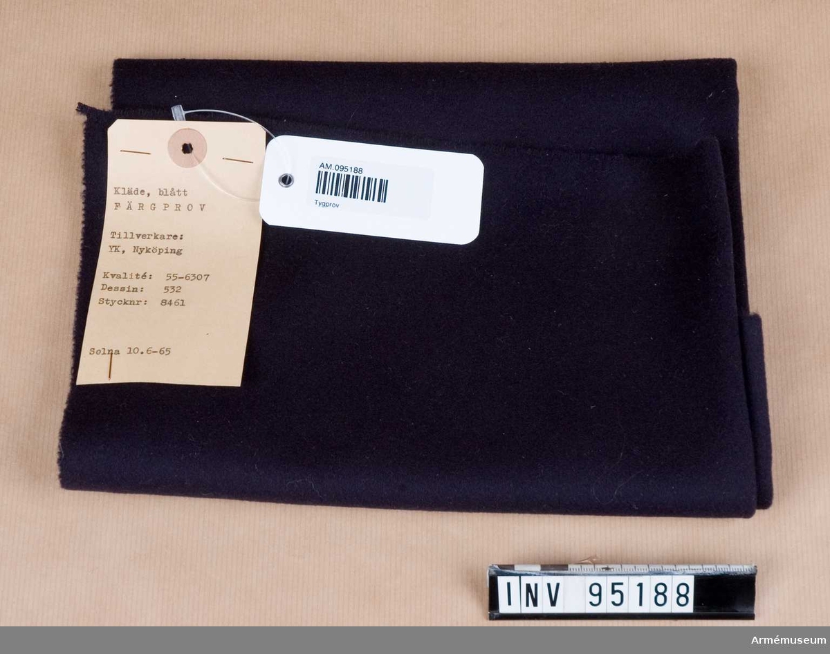 Text på etiketten: "Kläde, blått. FÄRGPROV Tillverkare: YK, Nyköping. Kvalité: 55-6307, Dessin: 532, Stycknr: 8461. Solna 10.6-65"