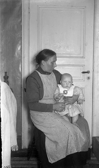 En kvinna sitter med ett spädbarn i famnen
