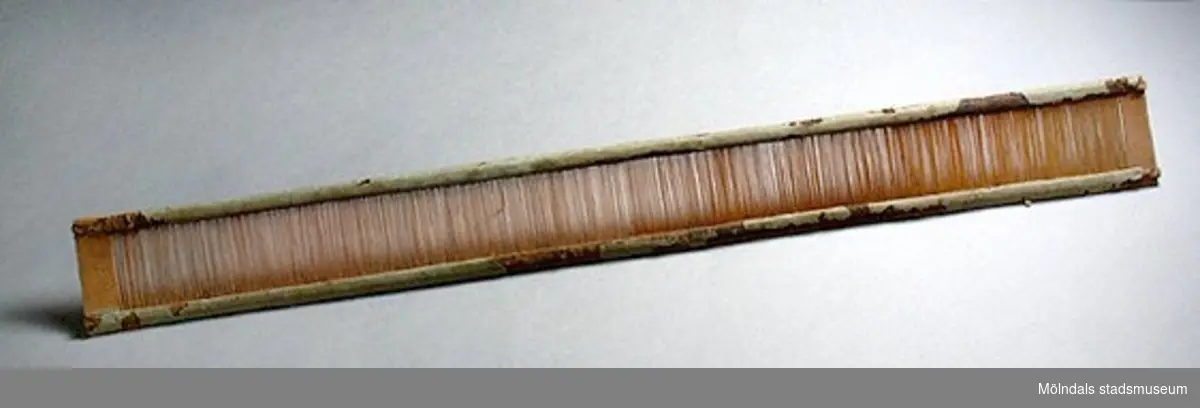 Vävsked med skedbredd 740 mm. Märkt på båda kortsidor: 80., samt HA på en sida och H på den andra. Långsidorna klädda med grönt papper - skadat på flera ställen. Under pappret garn (av hampa?). Tillverkad runt mitten på artonhundratalet. "Vävsked", även ritt eller vävkam, vävredskap bestående av en rad lameller ("tänder") i ett ramverk. Mellan lamellerna träs varptrådarna, varefter vävskeden sätts in i en slagbom. Källa: Nationalencyklopedin.