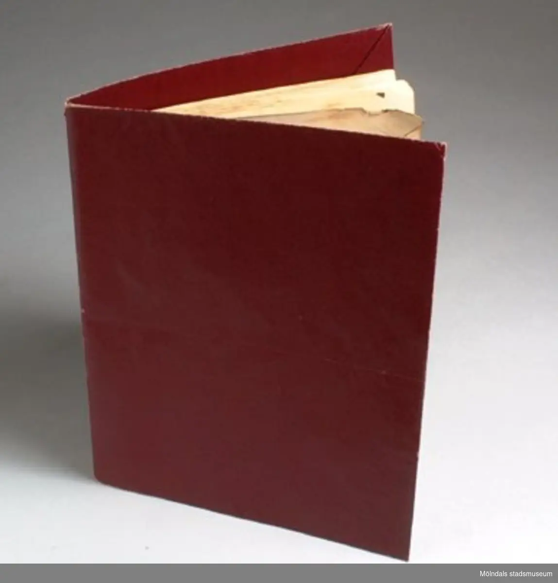 Pappersprov på s. k. väskpapper, vinrött. Har använts av Rut Larsson som bokomslag.