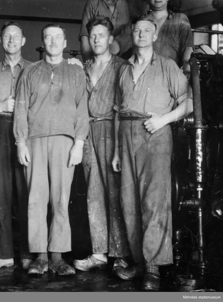 Papyrusarbetare uppställda framför maskinerna inuti fabriken ca 1930. 
Mannen till höger är Artur Svensson, född 1892.