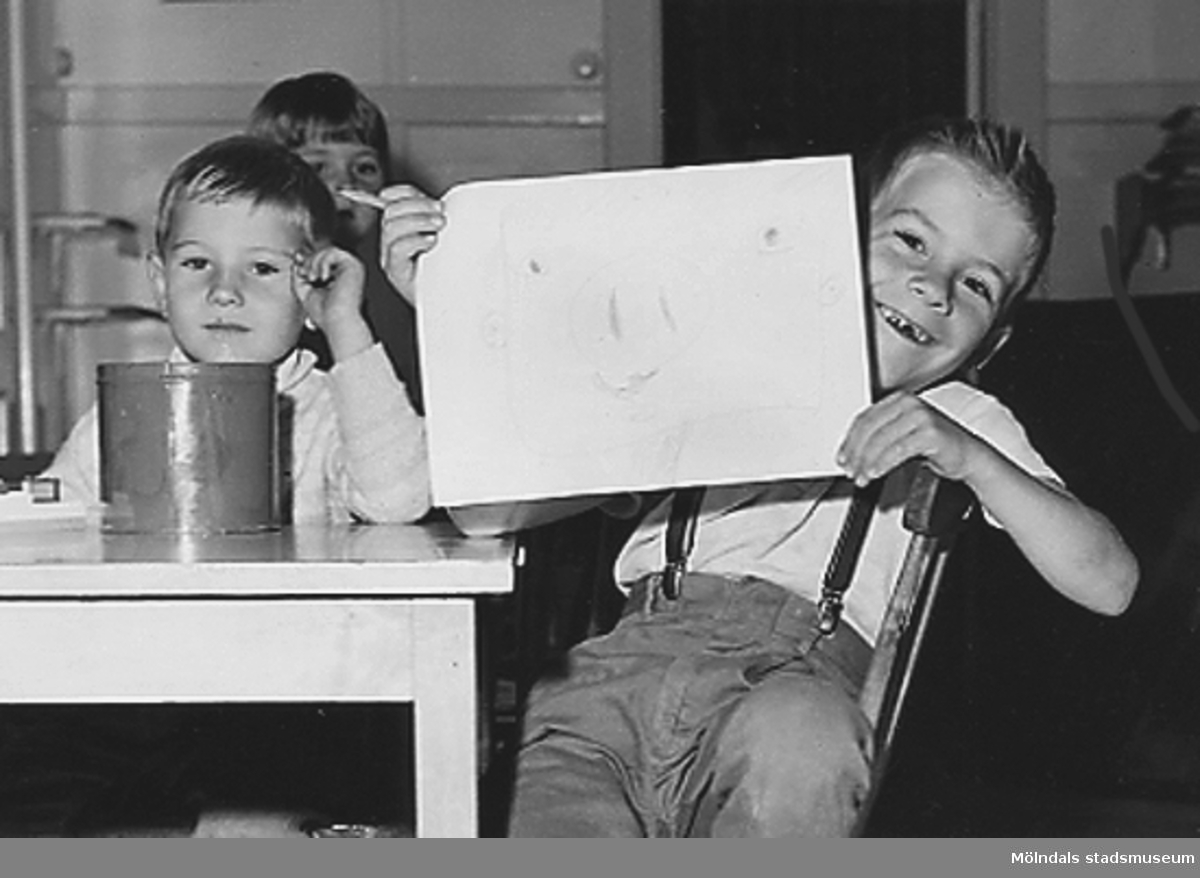 En leende pojke visar upp en teckning. Holtermanska daghemmet 1953.