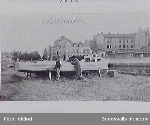 Två män vid en motorbåt på kajslänten på Norrmalm, öster om Storbron.
