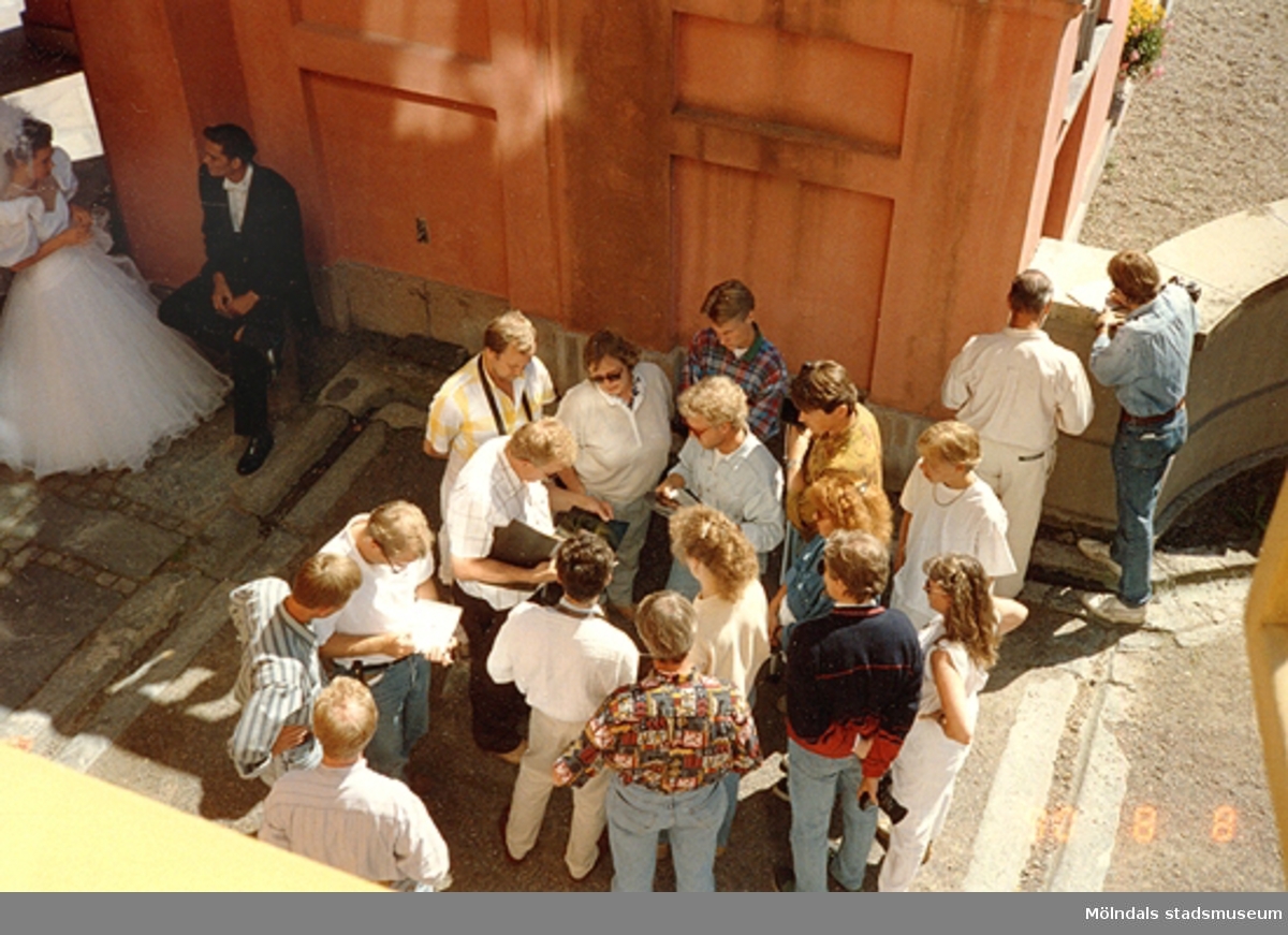 Till vänster ses ett brudpar som pratar. De befinner sig i valvet nedanför Gunnebo slottsterrass. Till höger står andra personer och samtalar, augusti 1990.