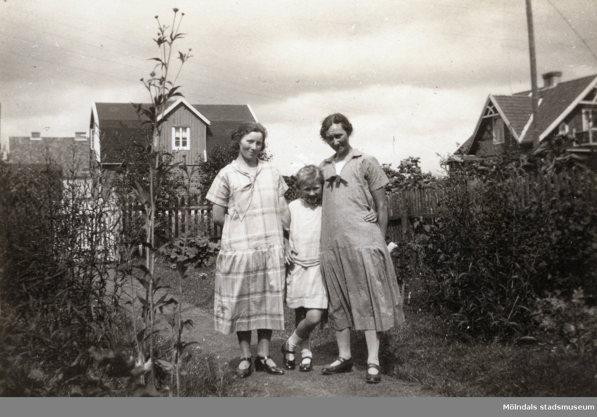 Elna Börjesson och Hilda Börjesson Hallgren fotograferade tillsammans med okänd kvinna i trädgården. Fotografi ur album som tillhört Hilda Börjesson Hallgren.
