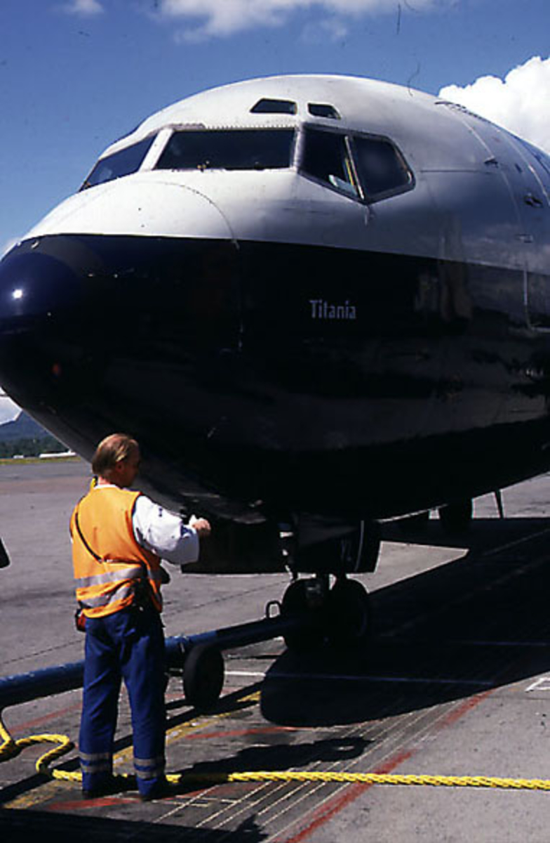 Lufthavn, 1 fly på bakken, Boeing 737 200, Titania, G-BKYL fra British Airways. 1 person, bakkemannskap, står under nesepartiet.