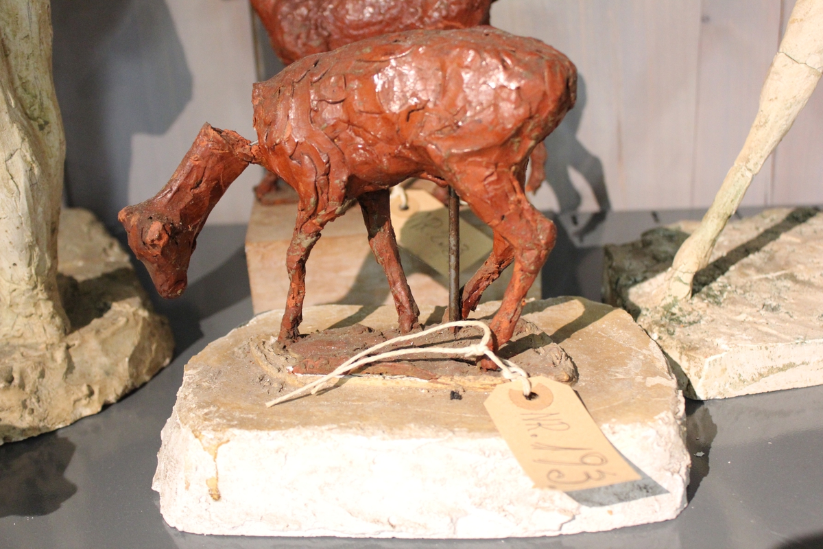 Skulptur av hjortedyr i rødbrunt kitt på sokkel av gips. Denne var et utkast.