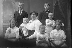 Studioportrett av en kvinne omgitt av syv barn.