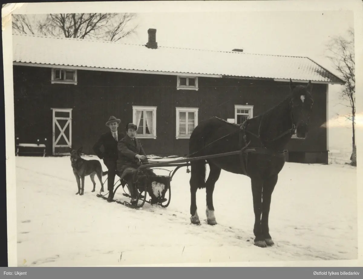 To ukjente menn med slede og hest, hund ved siden av. Uthuset på Yven gård, Tune i bakgrunnen, ca. 1924.