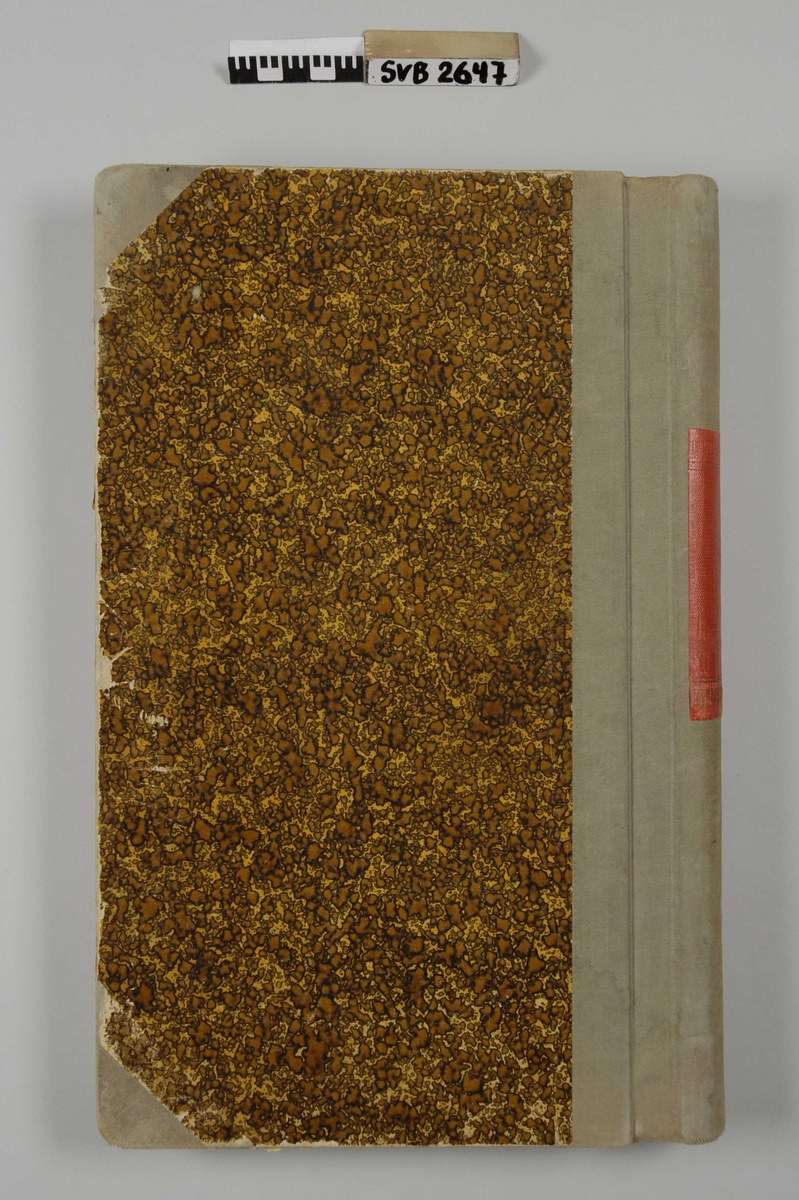 Notatbok med linjerte ark. Omslag med stive permer, rygg og hjørner trukket med beige tekstil. Omslaget er spettet brunt og gult. En rød tekstil-etikett på ryggen.
