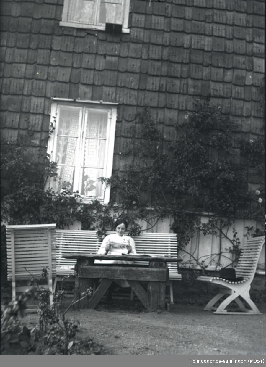 En kvinne sitter på en hagebenk foran Holmeegenes i Stavanger.