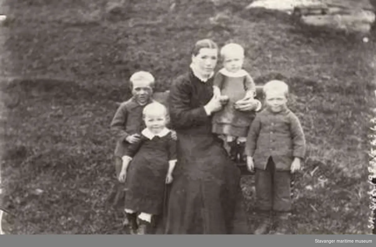 En kvinne i sort kjole m/ hvit krage, sammen med fire barn fra ca 2- 5 år. Sannsynligvis de fire yngste barna til Lauritz Haaland. Kvinnen er ukjent.