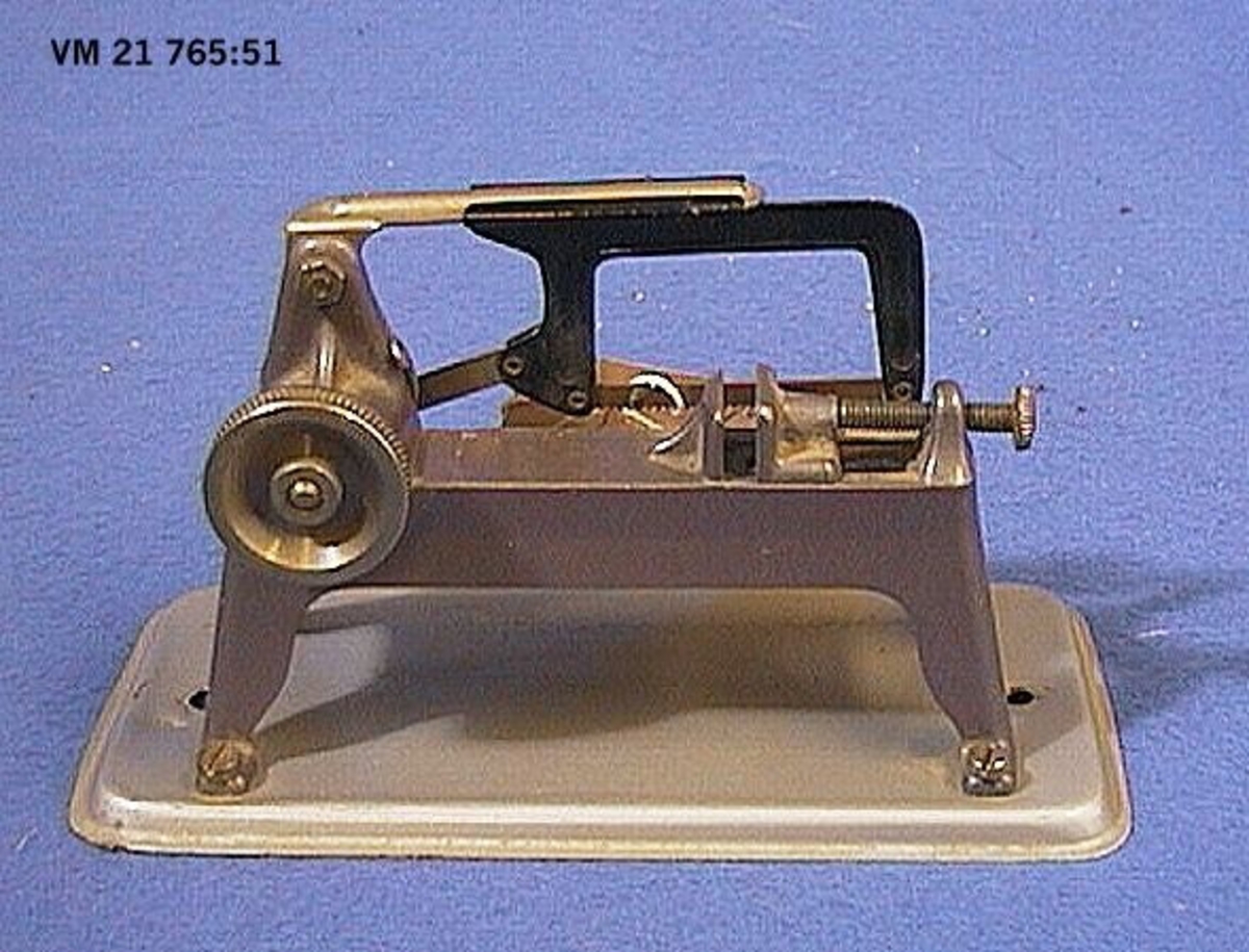 Tre tillbehör till ångmaskin, en man som drar en slipsten (tillverkad omkring 1940-talet), en såg (tillverkad omkring 1960-talet) samt en transmission för påhängande av drivlinor (tillverkad omkring 1970-talet). Den senare är tillverkad av Wilesco i Väst-Tyskland och förvaras i originalkartong.