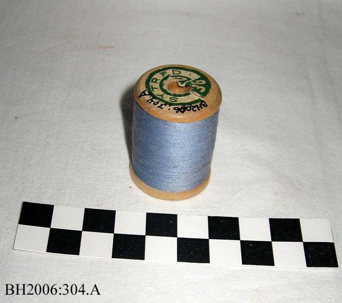 Trådsnelle med lys blå tråd, og kjerne av tre og etikett i hver ende.