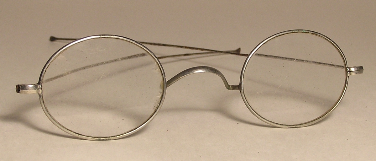 Oval tverrsnitt. Slank brillehus med briller. Briller har lange og  lett buet stenger.
