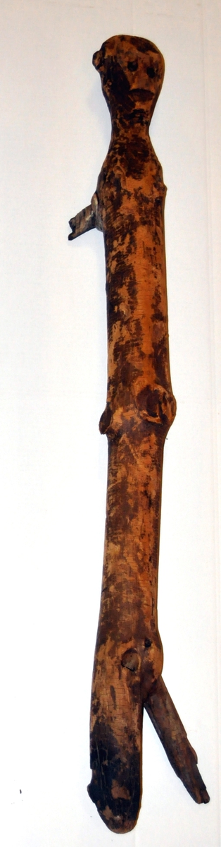 Fra protokollen: 2 husgudar (111 og 112) av gran, funne nedstungne i gormyr, saman med attributtar (3 tresnabbar). Nærmare "beskrivelse" av figurar, attributtar og fundtilhøve i R. Berge, Husgudar i Noreg (1921).
Trestokk formet som menneskelignende figur.
