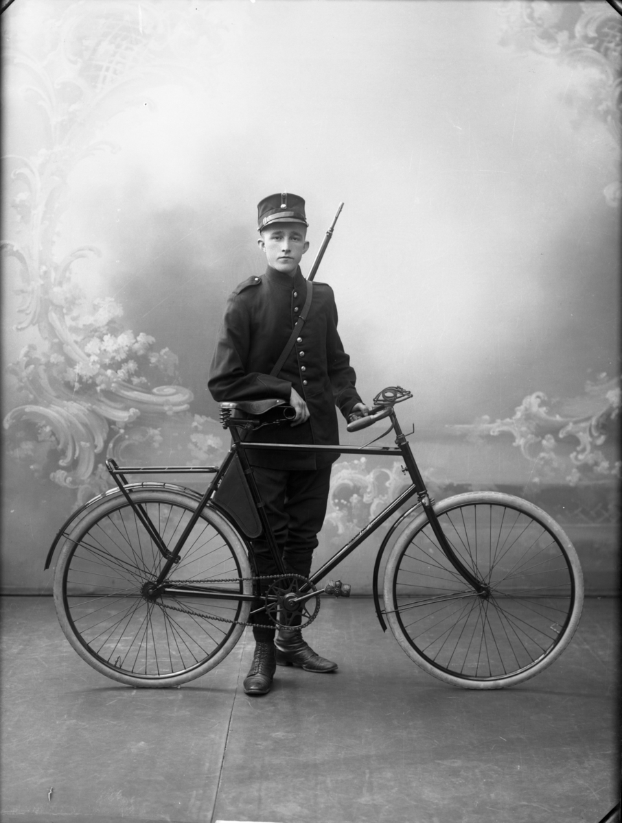 En ung mann i uniform med sykkel fotografert