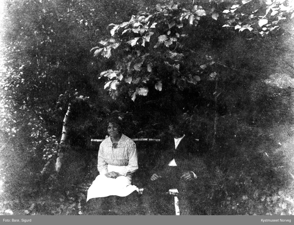Ukjent kvinne og mann på benk i en hage