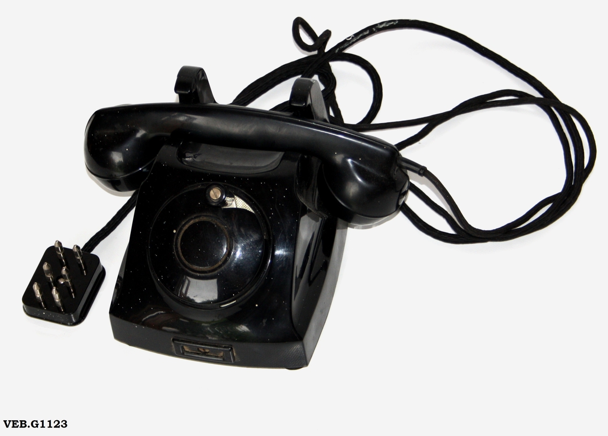 Kombinert bord- og veggtelefon med sveiv, modell 1953, produsert fra 1953 - 1967 av Elektrisk Bureau i et antall 151.400 apparater. Disse ble koblet til manuelle sentraler, hvor en sveivet mens røret lå på,for å sende ringestrøm til sentralen, hvor et flagg eller en klaff over linjejakken falt ned og sentralen kunne se hvilket nr. som ringte, og en ble satt over til ønsket tlf.nr. Kilde Telefonen - telefonapparater i Norge 1880 - 2000 Norsk Telemuseum