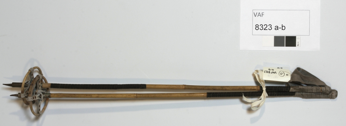 Skistaver, slalomstaver. Stenger (bambus) m/håndfeste m/lærløkke ene ende, metallspiss og ring (bambus) i lærfeste (i kryss) andre ende.