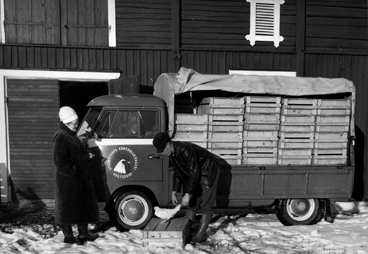 Stubbetorps Kontrollhönseri, lastbil och två personer.
Byggnad i bakgrunden.