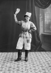 Skuespiller i kosakk-kostyme med tamburin. Kan være Signe He