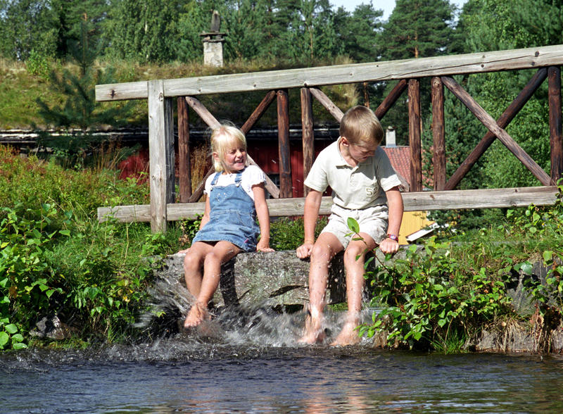 Barn som plasker med beina i dammen i museumsparken