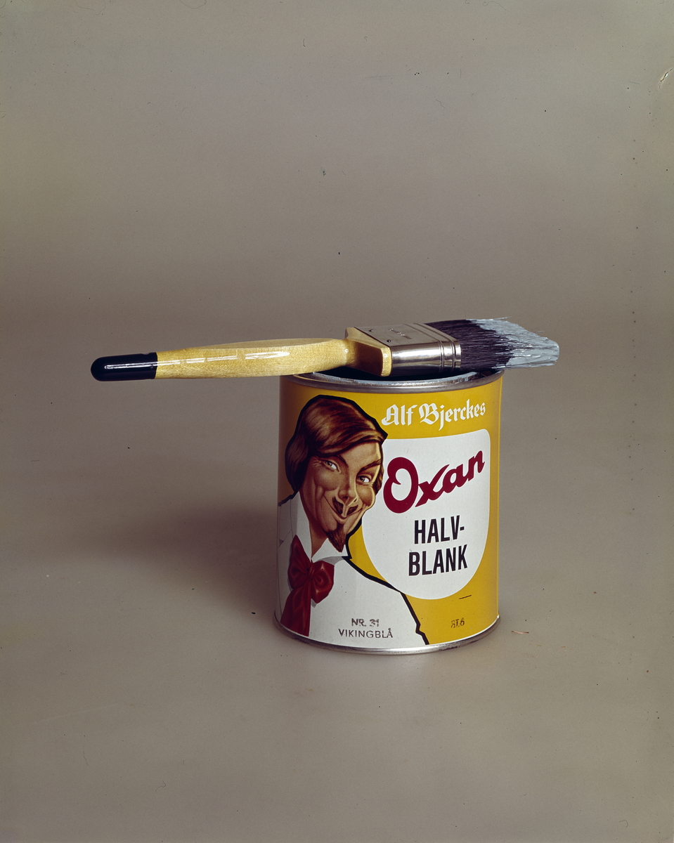 Produktfoto av et malingsspann med en pensel. Malingen er Alf Bjerckes Oxan halvblank..