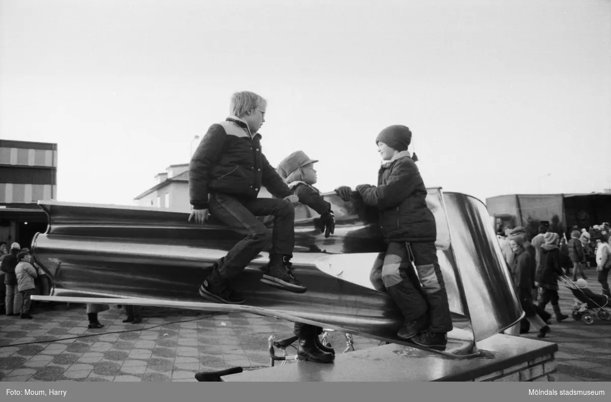 Underhållning i samband med Kållereds lucias kröning i Kållereds centrum, år 1983. Tre pojkar på den skulptur av Gino Scarpa som står på torget.

För mer information om bilden se under tilläggsinformation.
