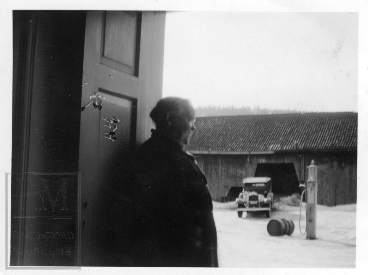 Bilde av Marte Stryken (f. Marte Grua) som står og ser utover en gårdsplass med en pumpe midt på og en bil og en låve i bakgrunnen.
