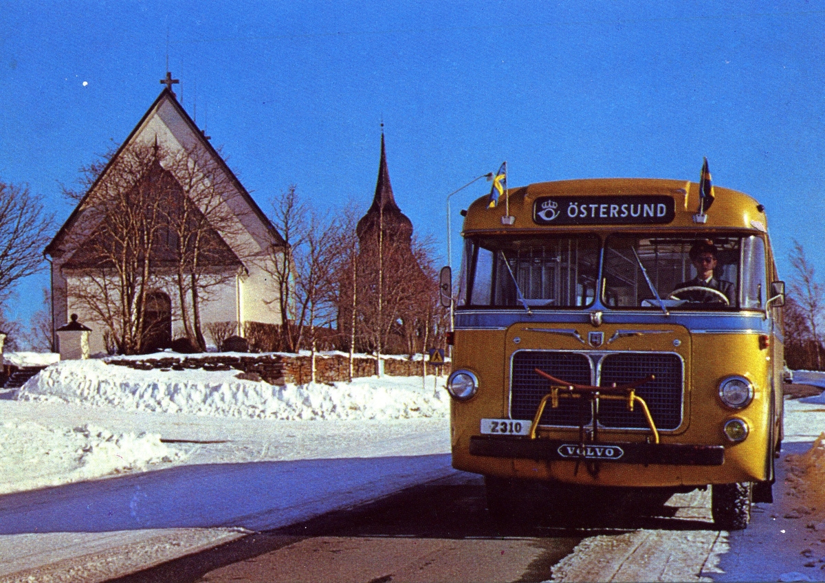 Vykort med motiv av en bildiligens, det vill säga en buss som i linjetrafik tog post och passagerare i Norrland. Bussens namnskylt visar "Östersund" och bilden är tagen vid en kyrka, vintertid. Vykortet är inte postbehandlat.