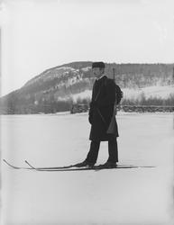 Mann på ski med Krag-Jørgensengevær, jorde, steinmur