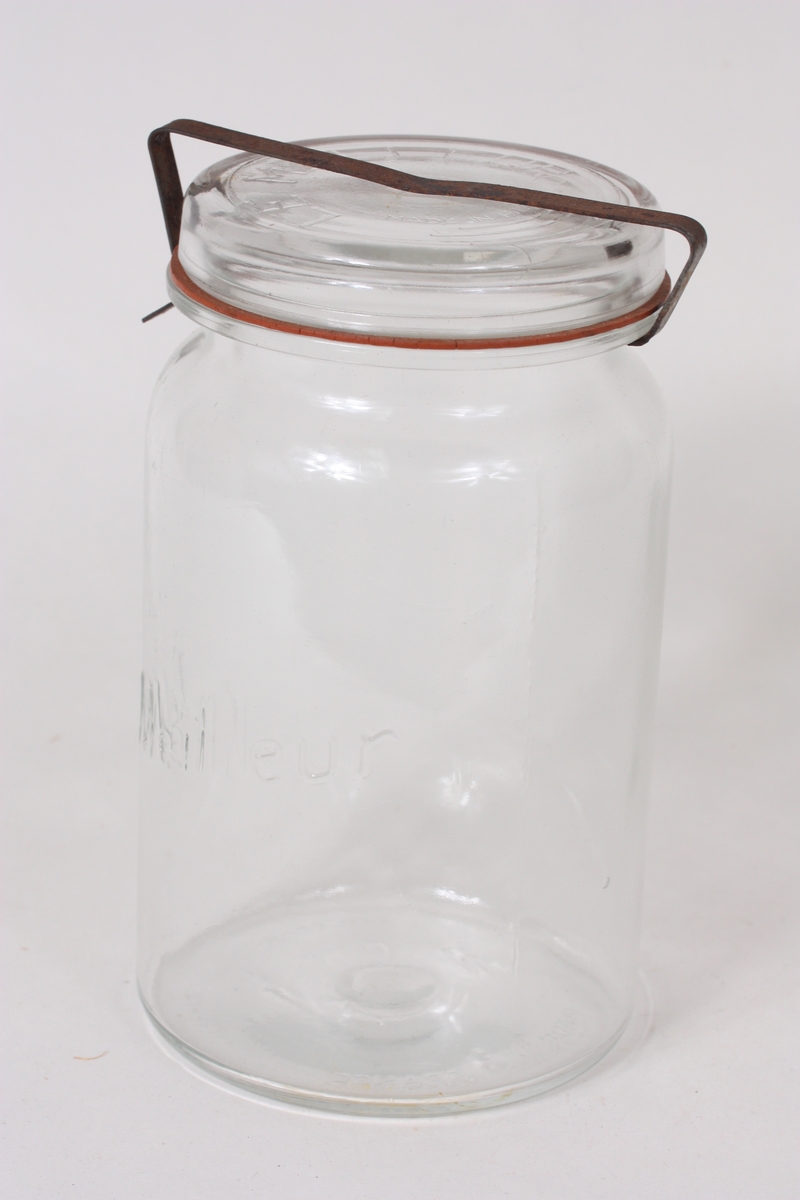 Sylindrisk glas med lok som blir halde på plass med ei metallklemme