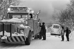 Bergingsvogn hjelper en buss opp av grøfta. To skoleunger st