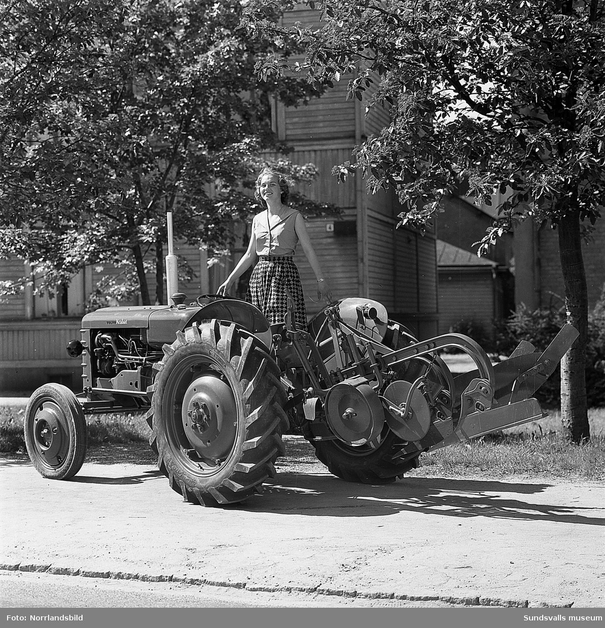 Två unga kvinnor visar upp en liten jordbrukstraktor, Volvo Krabat,  på Parkgatan. På en av bilderna skymtar den numera rivna fastigheten på Parkgatan 4.