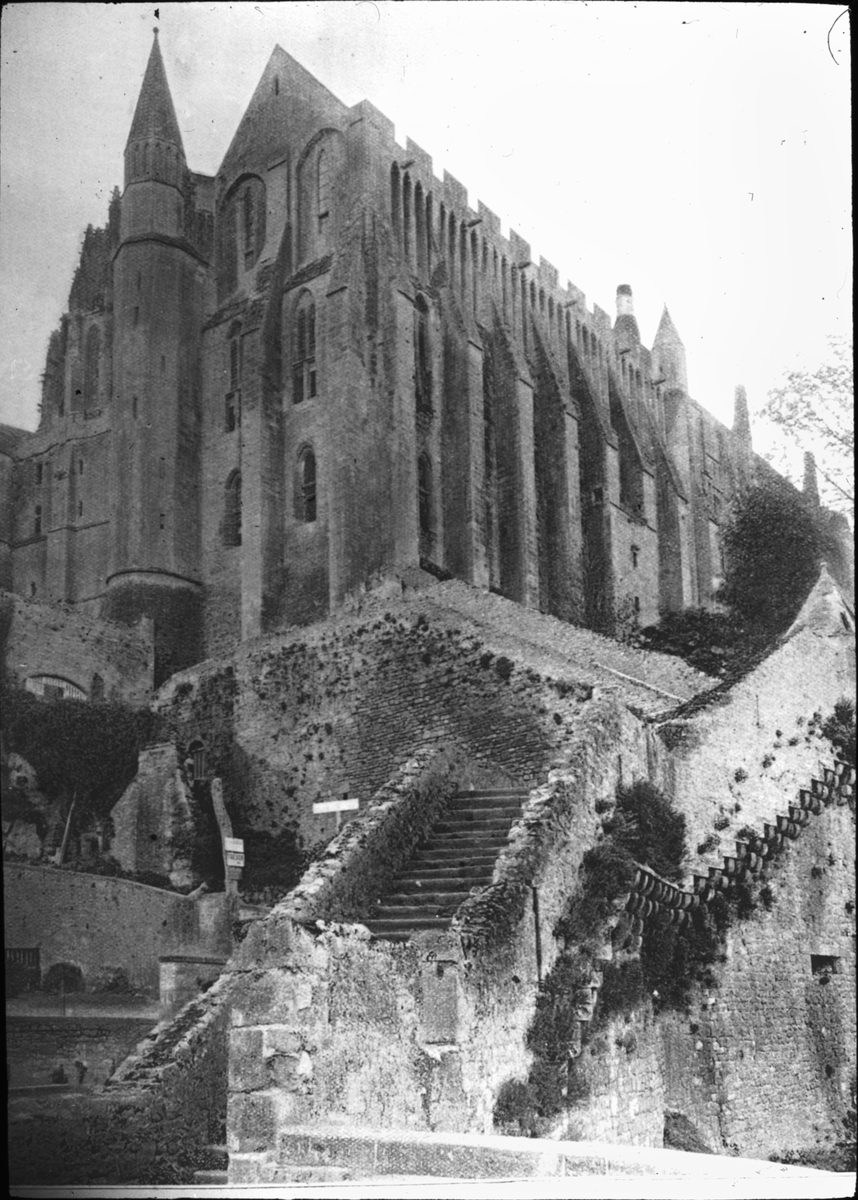 Skioptikonbild med motiv av kyrkan i Mont Saint-Michel.
Bilden har förvarats i kartong märkt: Resan1908 XIV. St. Michel 7. Dinan 1.. Text på bild: "Abbaye du Mont St. Michel, La Merville (Faees Nord et Est)"