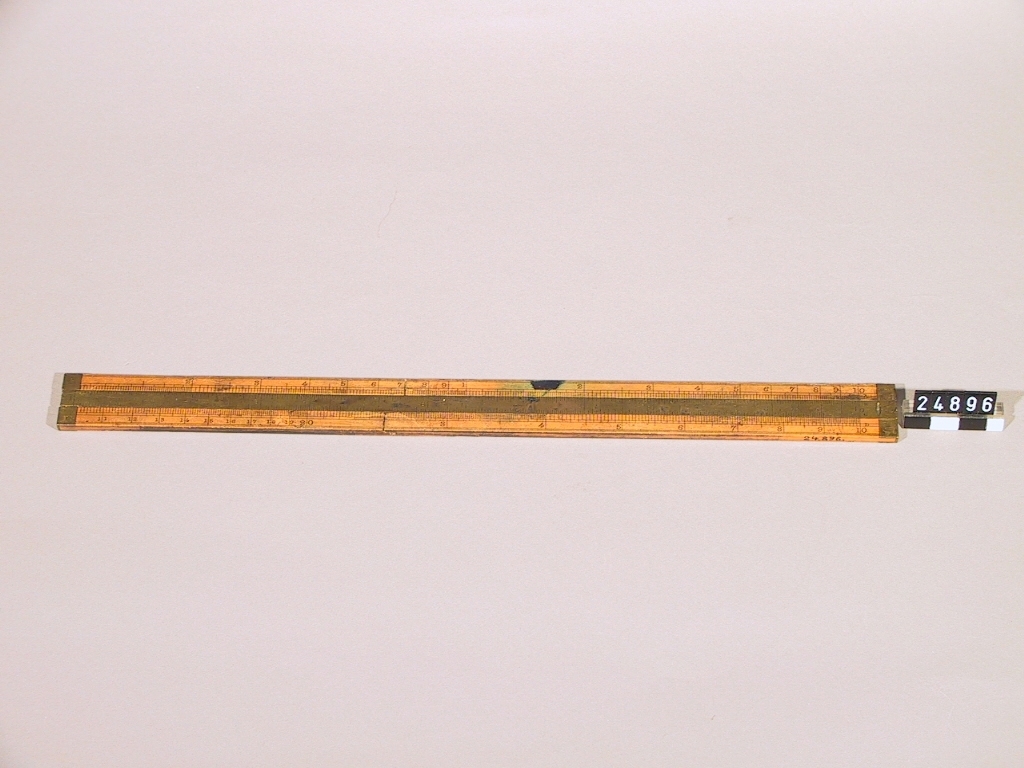Räknesticka av buxbom, med två logaritmiska skalor och för cm och svenska decimaltum. Stickan var vid ankomsten till TM bruten i tre delar, sammanhållna av mässing sliden. Stämplad: "Carl Löf".