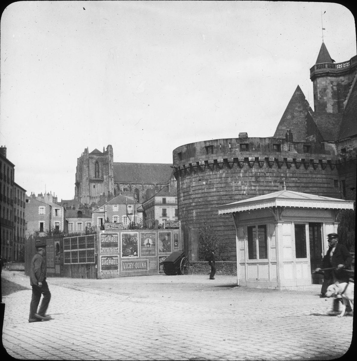 Skioptikonbild med motiv av slottet Le Château des Ducs de Bretagne och katedralen Cathédrale St. Pierre (St. Paul). 

Bilden har förvarats i kartong märkt: Resan 1908. Vannes. XXI. Text på bild: "Slott och katedral".
