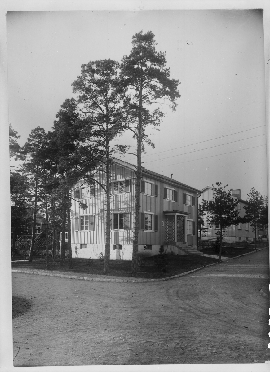 Bygge och Bo-utställningen i Äppelviken 1927. Kung Gustaf V vid invigningen. Exteriörbild av hus med veranda.
Huset finns kvar på Ekorrvägen 18.