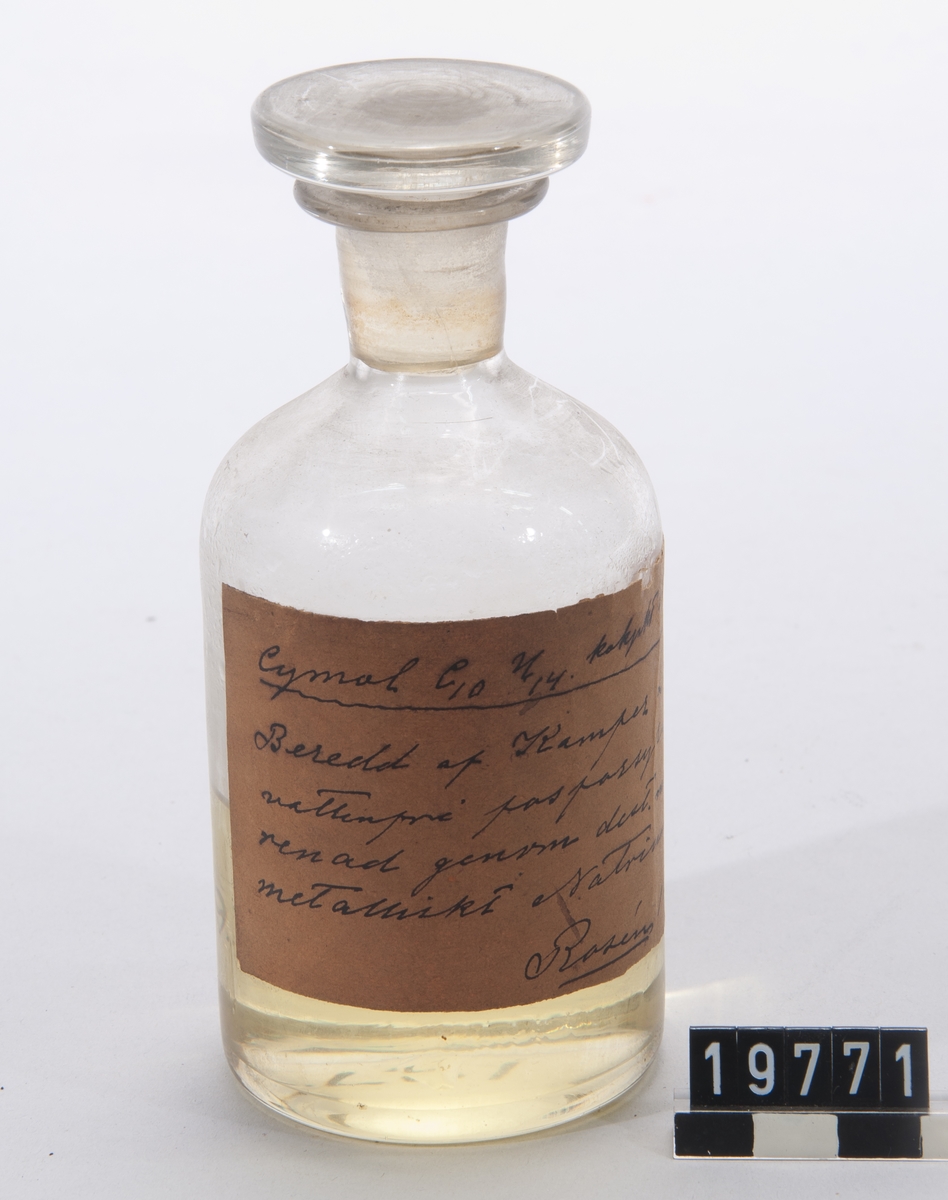 Prov på cymol, framställd av kamfer och fosforsyra, i flaska av glas med etikett, signerad Rosén.